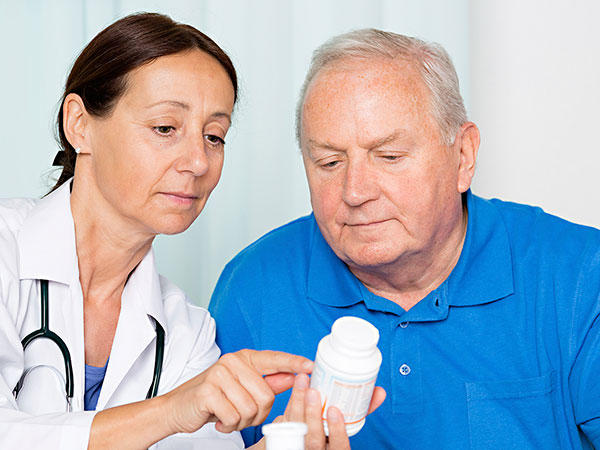 Una médica muestra a un paciente un frasco de medicamento.