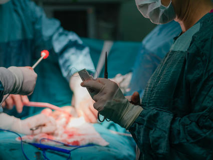 A surgical team standing over a patient in the operating room.