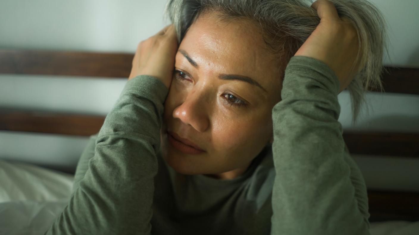 Woman holding her head in pain while crying