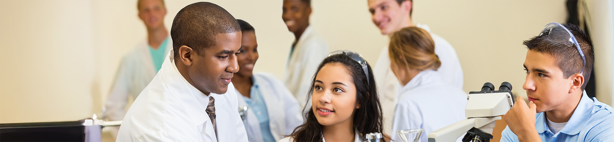 A researcher in a lab coat instructs two students