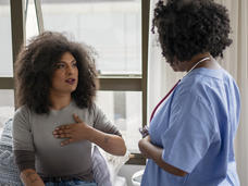 Photo of a transgender woman speaking with a health care provider wearing blue scrubs.